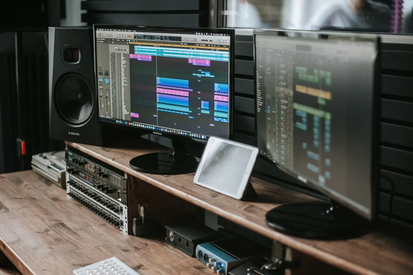 Audio software on two monitors beside a studio speaker.